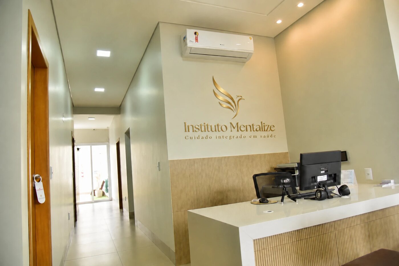 Recepção do Instituto Mentalize, com o logo em dourado na parede e o corredor de acesso aos consultórios